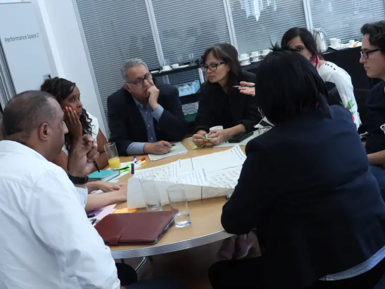 Group of people sat around a desk talking.