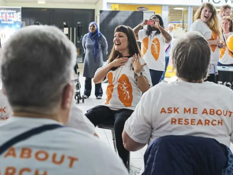 Person leading group in breathing exercises whilst sitting.