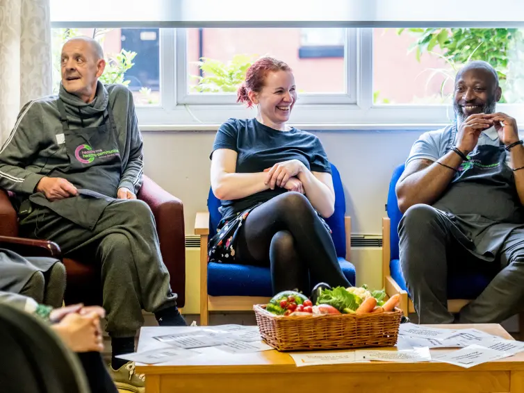 Three people sat down talking and smiling.