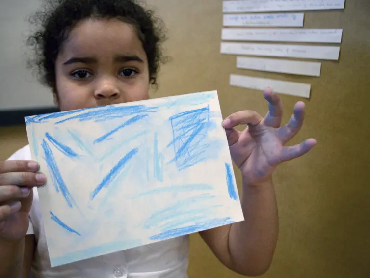 Little girl holding a colourful drawing.