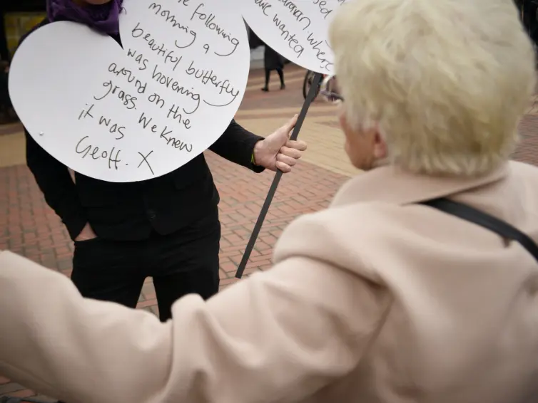 Back of a woman's head as she looks at writing on a white board in the street.