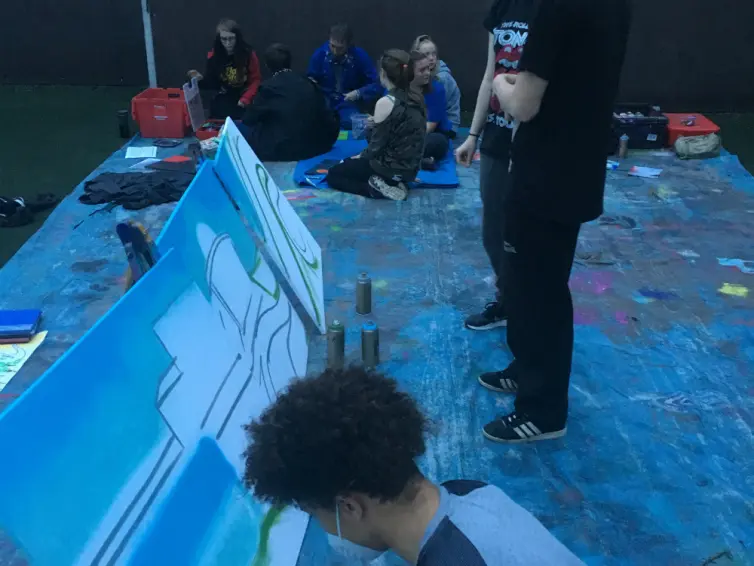 Young people painting a banner outside.