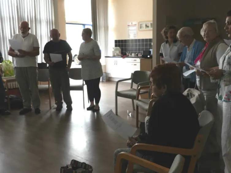 Image of people standing in a circle singing.