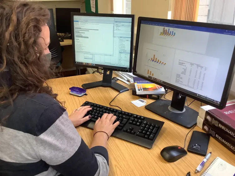 Person typing at computer with two screens.