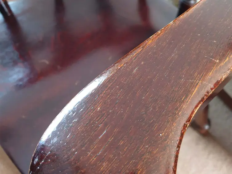 A close up of a wooden chair with signs of wear.