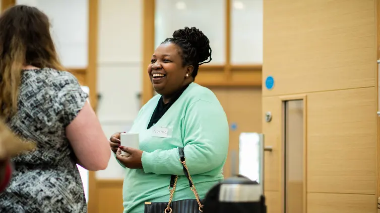 Person smiling at another person talking to her.