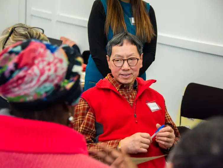 Person sat down with others listening to them.