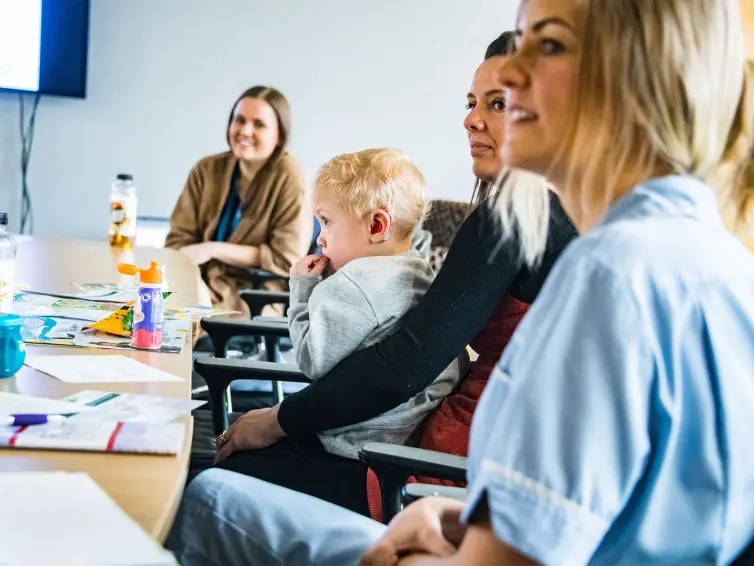 People around a table with a baby, all smiling.