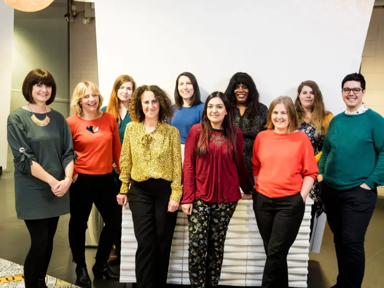 10 people standing in 2 rows, smiling.